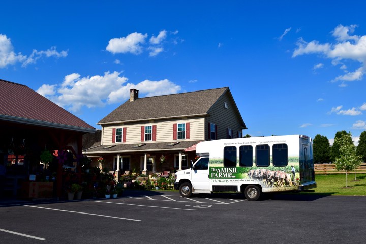 A white van parked outside a farmhouse with a clear blue sky.
