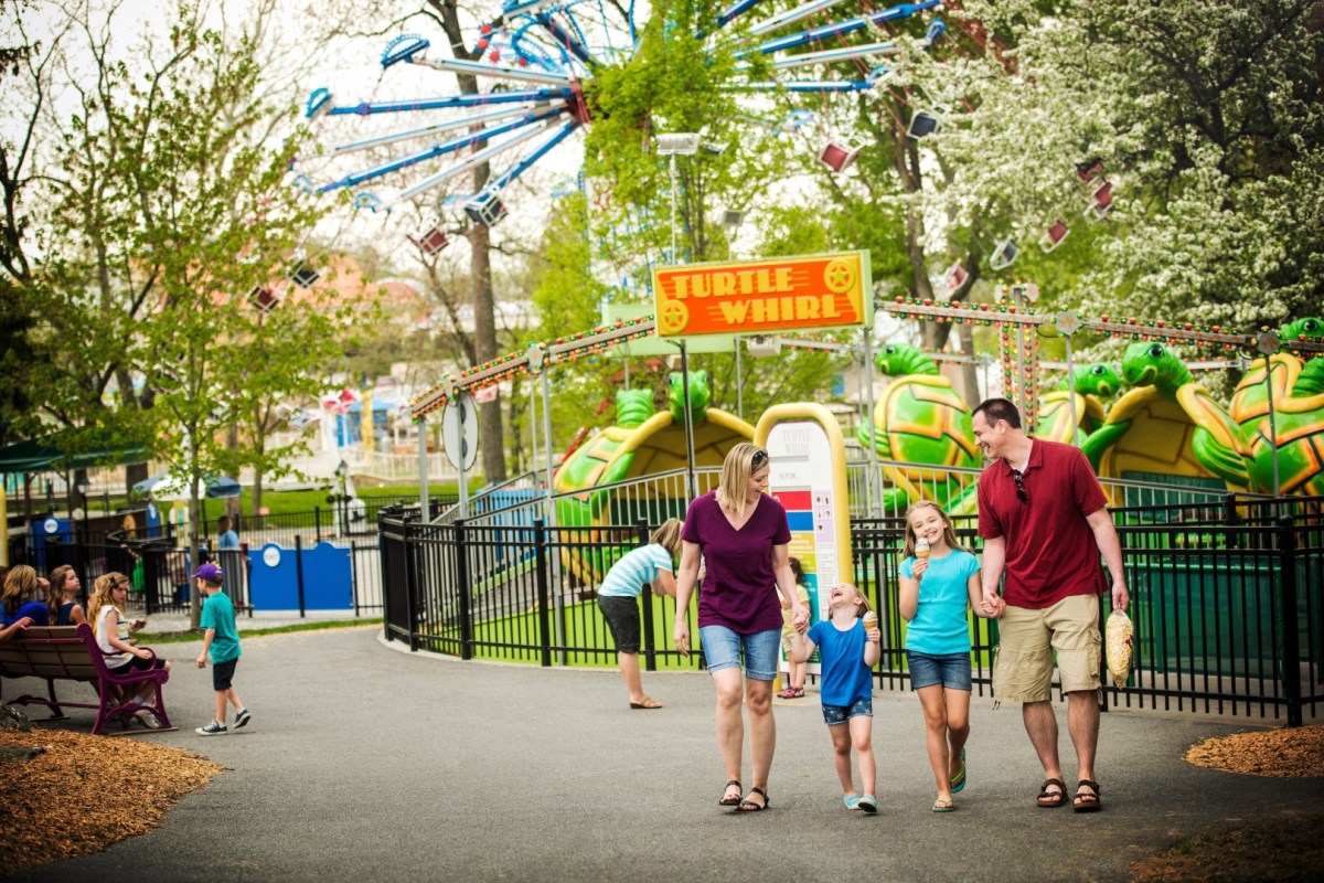 Family with two children walking near Turtle Whirl ride at an amusement park.